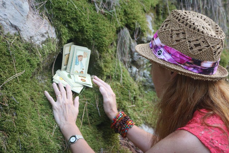 Las manos de Cristina sobre una baraja apoyada en el musgo