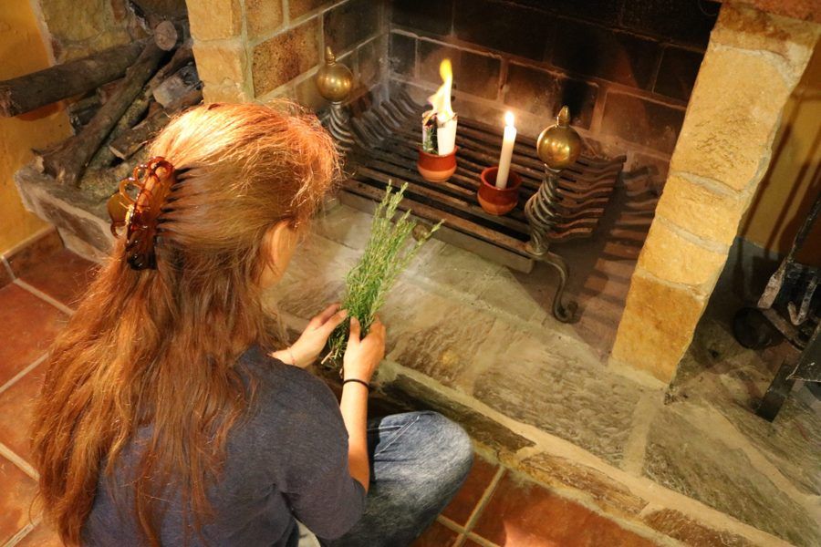 Cristina preparando un ritual con romero y velas junto a la chimenea